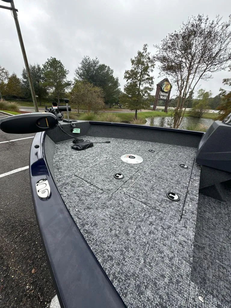 Slide: The Image of 2025 Tracker Pro Guide V-16 SC boat deck with fishing equipment, parked outdoors. - 4