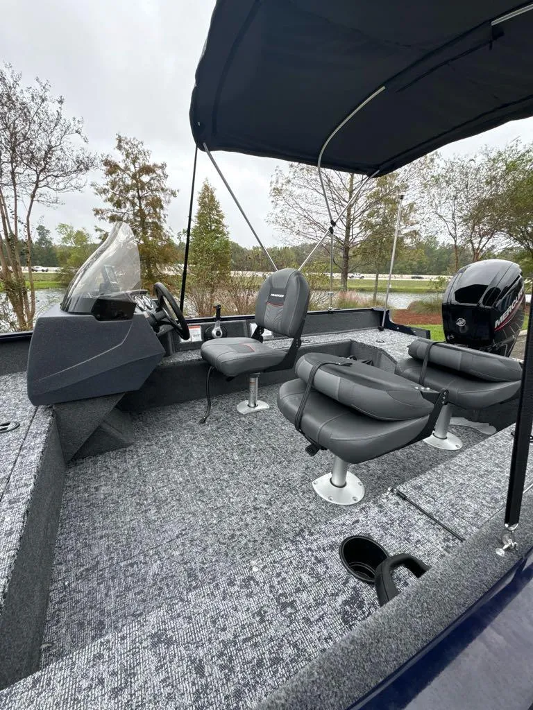 Slide: The Image of 2025 Tracker Pro Guide V-16 SC boat with seating and canopy on a lake. - 5