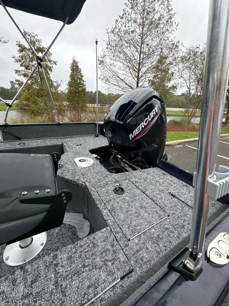 Slide: The Image of 2025 Tracker Pro Guide V-16 SC boat with Mercury engine, parked outdoors. - 6