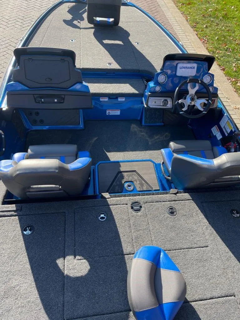 Slide: The Image of 2025 Nitro Z20 XL boat interior with blue and gray seating, steering console, and carpeted deck. - 3