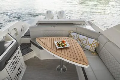 Slide: The Image of 2025 Sea Ray SLX 310 Outboard interior with elegant seating and wooden table by the water. - 10
