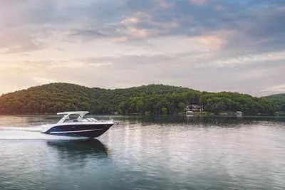 Slide: The Image of 2025 Sea Ray SLX 310 Outboard cruising on a serene lake at sunset. - 2