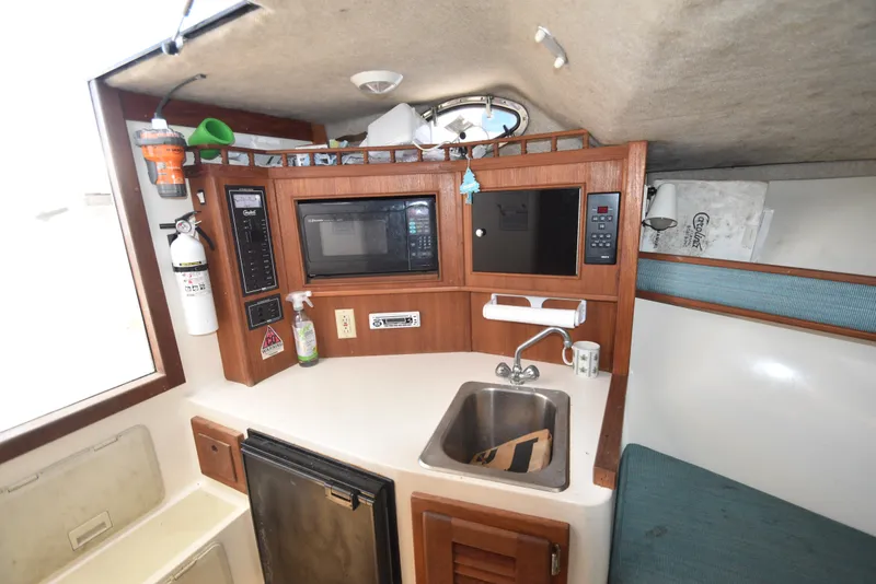 Slide: The Image of 1999 Carolina Classic 28 Express boat interior with kitchenette, sink, microwave, and storage. - 18
