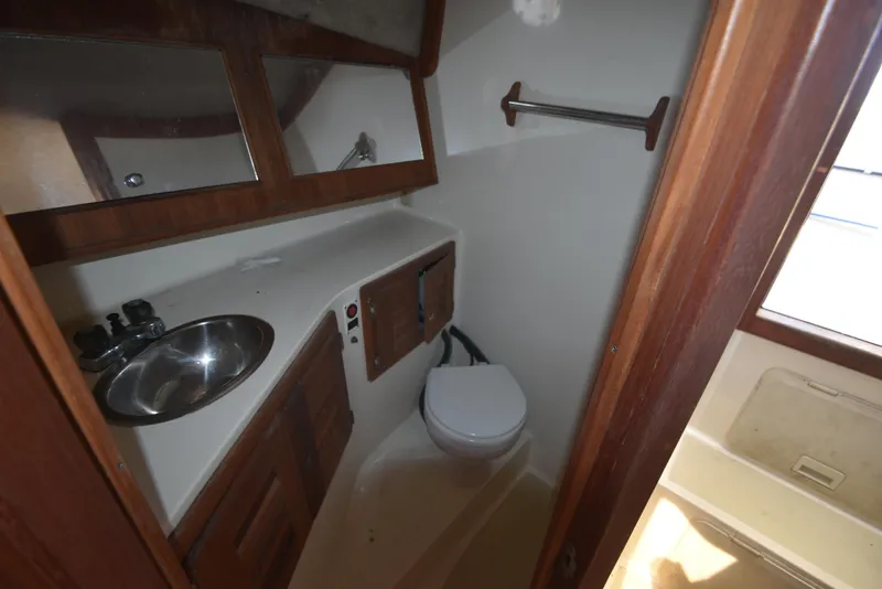 Slide: The Image of 1999 Carolina Classic 28 Express boat bathroom with sink, toilet, and wooden cabinets. - 24