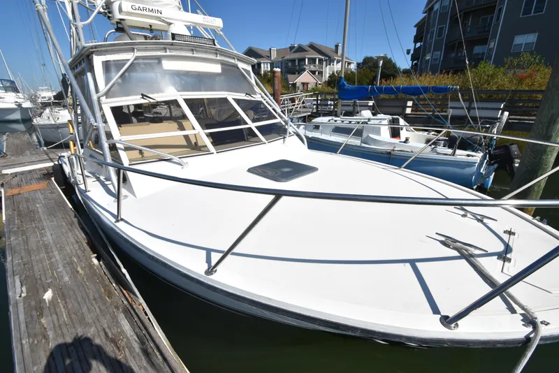 Slide: The Image of 1999 Carolina Classic 28 Express boat docked at marina, featuring sleek design and Garmin equipment. - 25