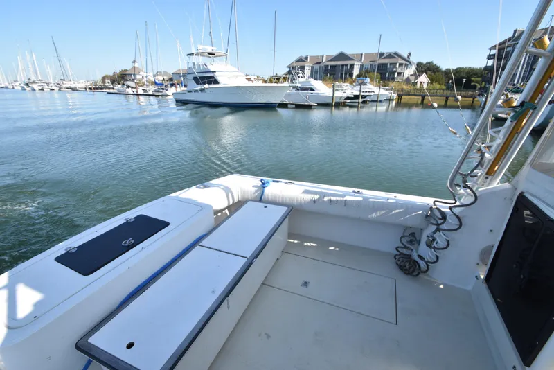 Slide: The Image of 1999 Carolina Classic 28 Express boat docked in a marina with other vessels. - 6