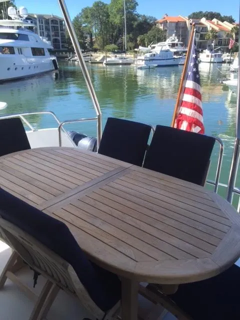 Slide: The Image of 1998 Hatteras 74 Sport Deck yacht with outdoor dining area, docked in a marina. - 19