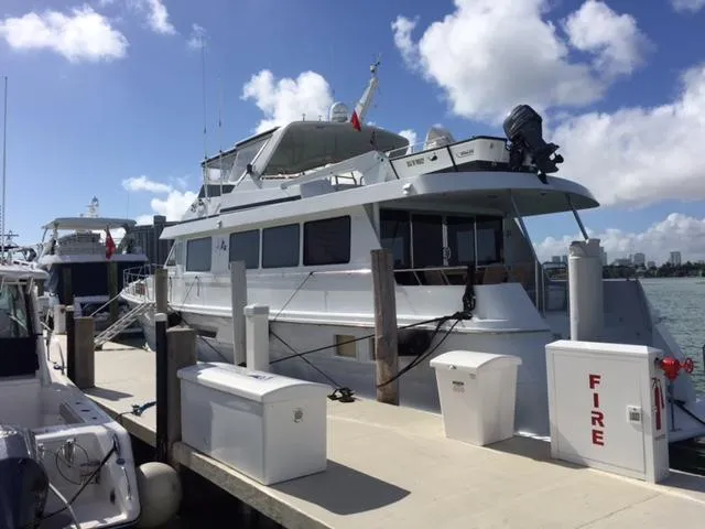 Slide: The Image of 1998 Hatteras 74 Sport Deck yacht docked at marina under blue sky. - 25