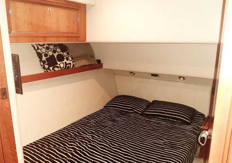 Slide: The Image of 2009 Riviera 47 Enclosed Flybridge Series II cabin with striped bedding and wooden storage. - 17