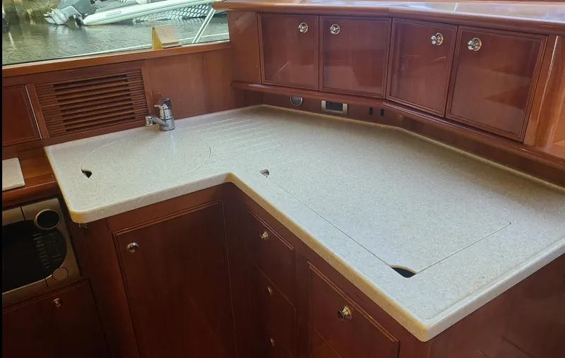 Slide: The Image of 2009 Riviera 47 Enclosed Flybridge Series II yacht kitchen with wooden cabinets and countertop. - 28