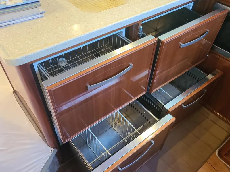 Slide: The Image of Kitchen drawers in a 2009 Riviera 47 Enclosed Flybridge Series II yacht, featuring sleek wooden design. - 29