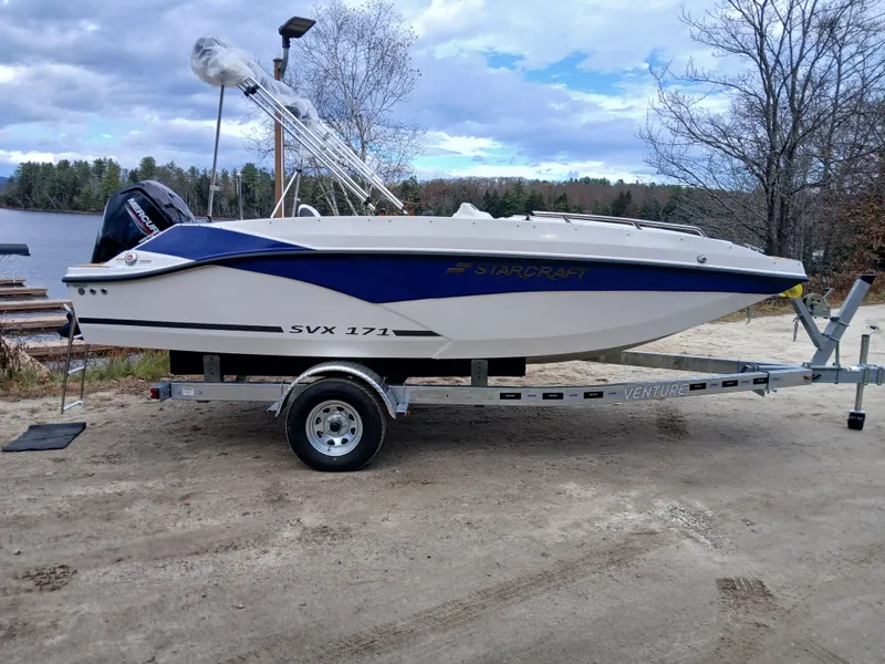 Slide: The Image of 2025 Starcraft SVX 171 OB boat on trailer by a lake. - 1
