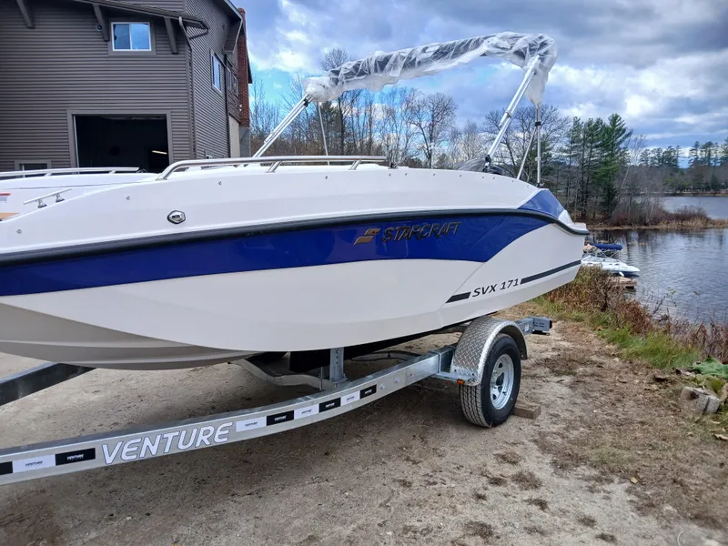 Slide: The Image of 2025 Starcraft SVX 171 OB boat on trailer by a lake. - 3