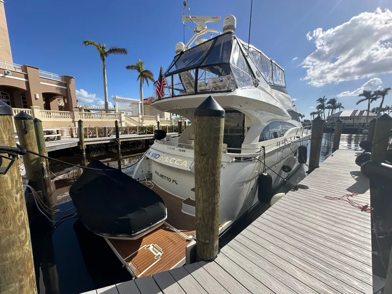 Slide: The Image of Luxury 2004 Marquis 59 yacht docked at marina under clear blue sky. - 2