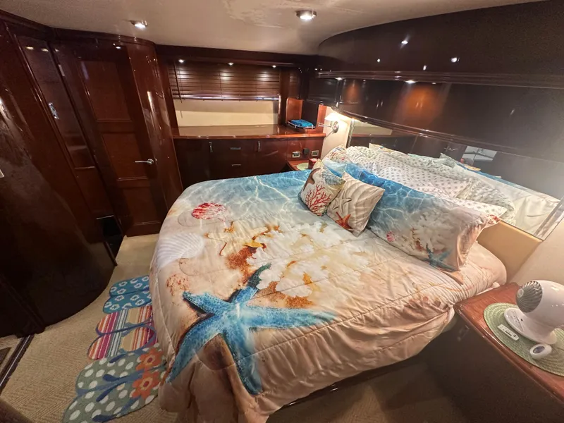 Slide: The Image of Luxurious 2004 Marquis 59 yacht bedroom with ocean-themed bedding and elegant wood finishes. - 20