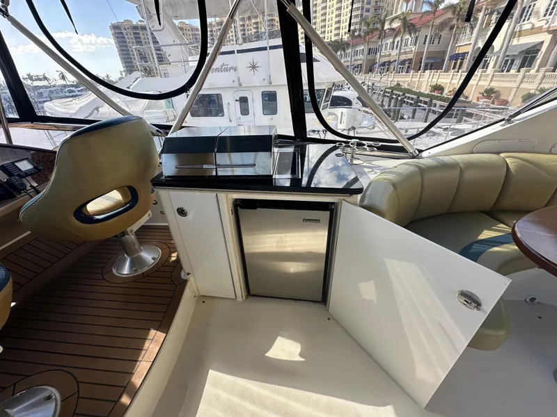 Slide: The Image of Luxurious 2004 Marquis 59 yacht interior with seating, mini fridge, and marina view. - 30