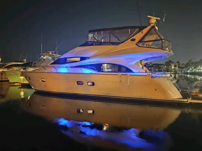 Slide: The Image of 2004 Marquis 59 yacht illuminated at night with blue lights, docked in a marina. - 6