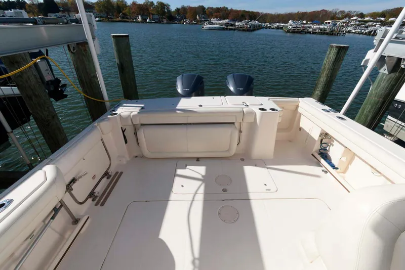 Slide: The Image of 2015 Grady-White Freedom 335 boat deck with dual engines, docked by the water. - 14