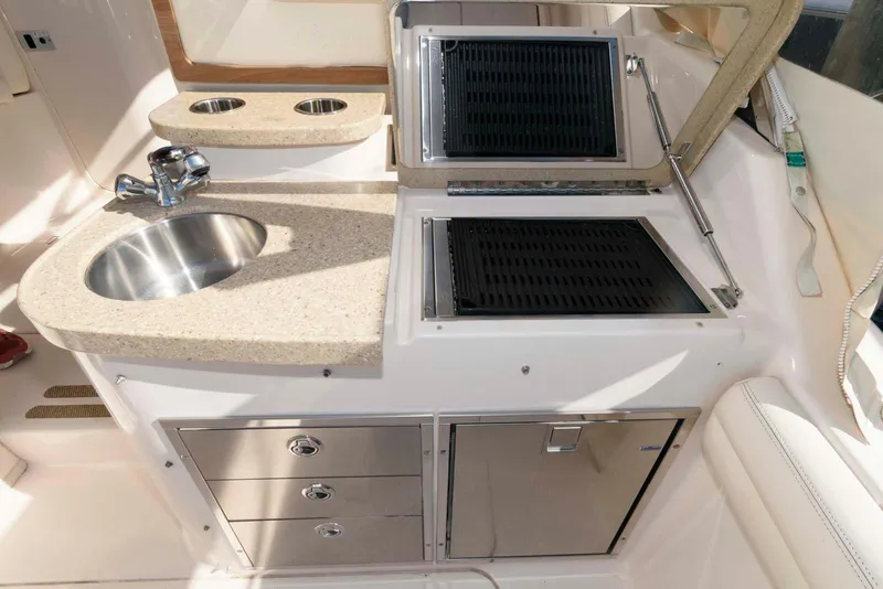 Slide: The Image of 2015 Grady-White Freedom 335 boat kitchen with sink, grill, and storage drawers. - 16