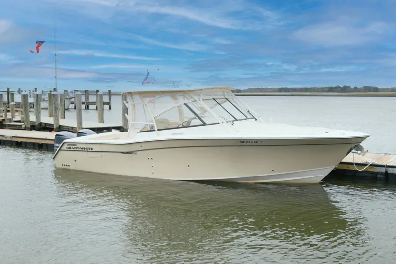 Slide: The Image of 2015 Grady-White Freedom 335 boat docked on calm water under a blue sky. - 2