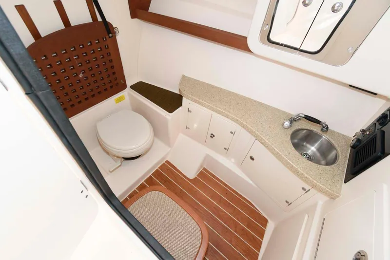 Slide: The Image of 2015 Grady-White Freedom 335 boat interior with toilet, sink, and wooden flooring. - 24