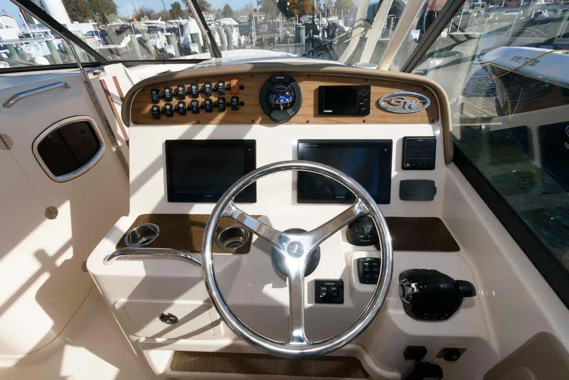 Slide: The Image of 2015 Grady-White Freedom 335 boat dashboard with steering wheel and control panels. - 7