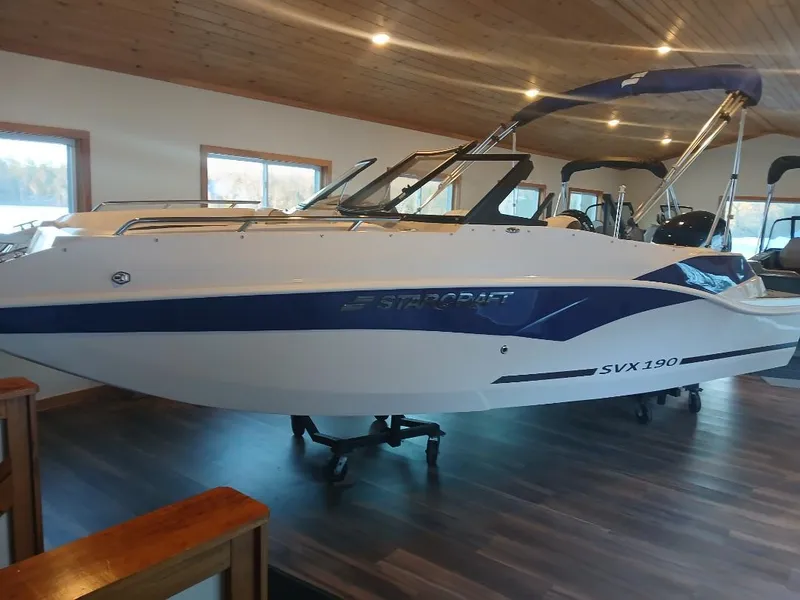 Slide: The Image of 2025 Starcraft SVX 190 OB boat displayed indoors with blue accents and canopy. - 0