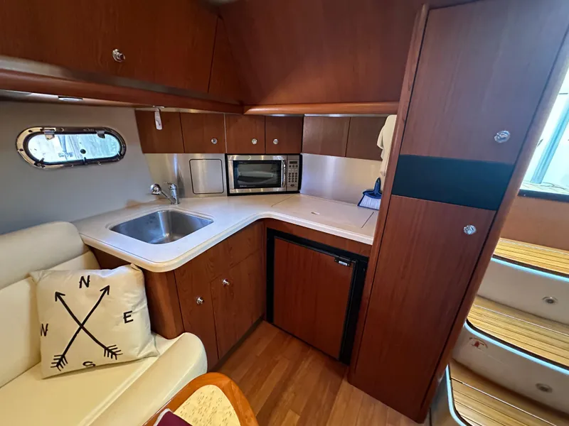 Slide: The Image of 2005 Tiara Yachts 3600 Sovran interior kitchen with sink, microwave, and wooden cabinetry. - 41