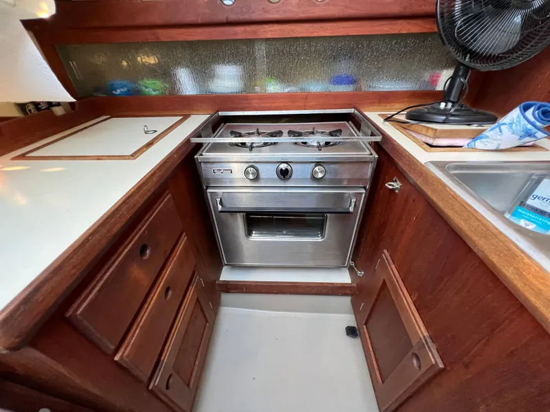 Slide: The Image of 1983 O'Day 34 yacht kitchen with stove, wooden cabinets, and sink. - 20