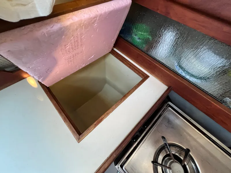 Slide: The Image of 1983 O'Day 34 boat interior with open storage compartment and stove. - 22