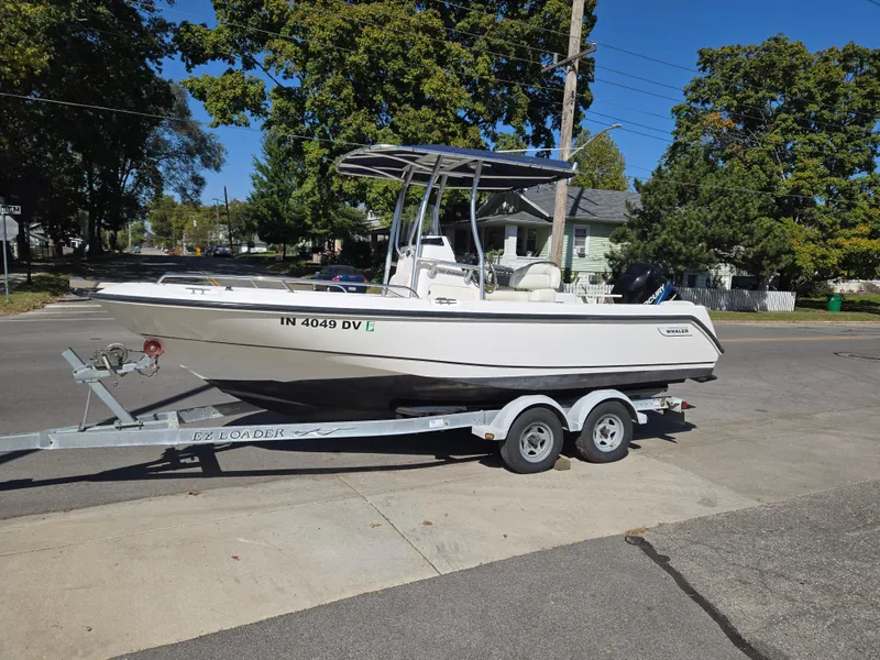 Slide: The Image of 2004 Boston Whaler 210 Outrage boat on trailer, parked on a sunny street. - 3