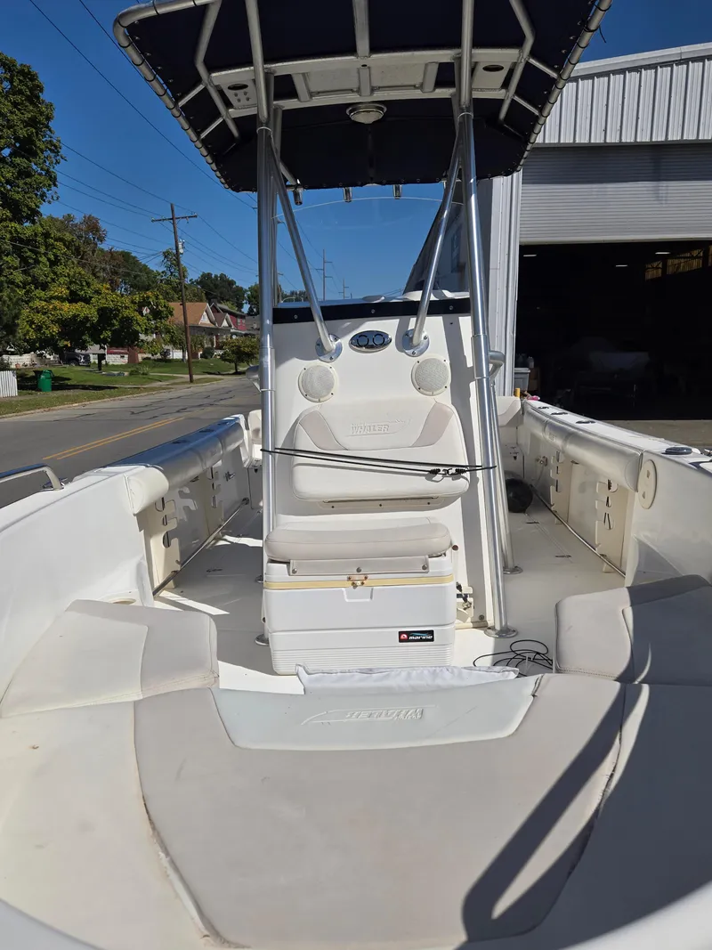 Slide: The Image of 2004 Boston Whaler 210 Outrage boat interior with seating and console, parked outdoors. - 5