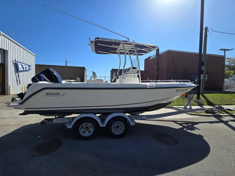 Slide: The Image of 2004 Boston Whaler 210 Outrage boat on trailer, parked outdoors. - 8