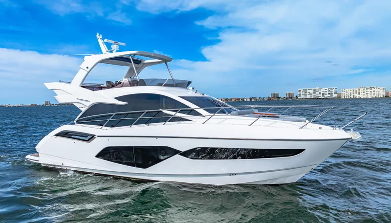 Slide: The Image of 2021 Sunseeker Manhattan 55 yacht cruising on open water under a clear blue sky. - 11