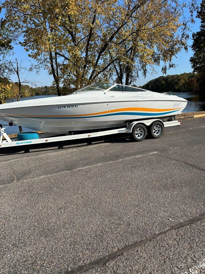 The Image of 1995 Baja 272 Islander boat on trailer, parked near a scenic lake with autumn trees. - 1