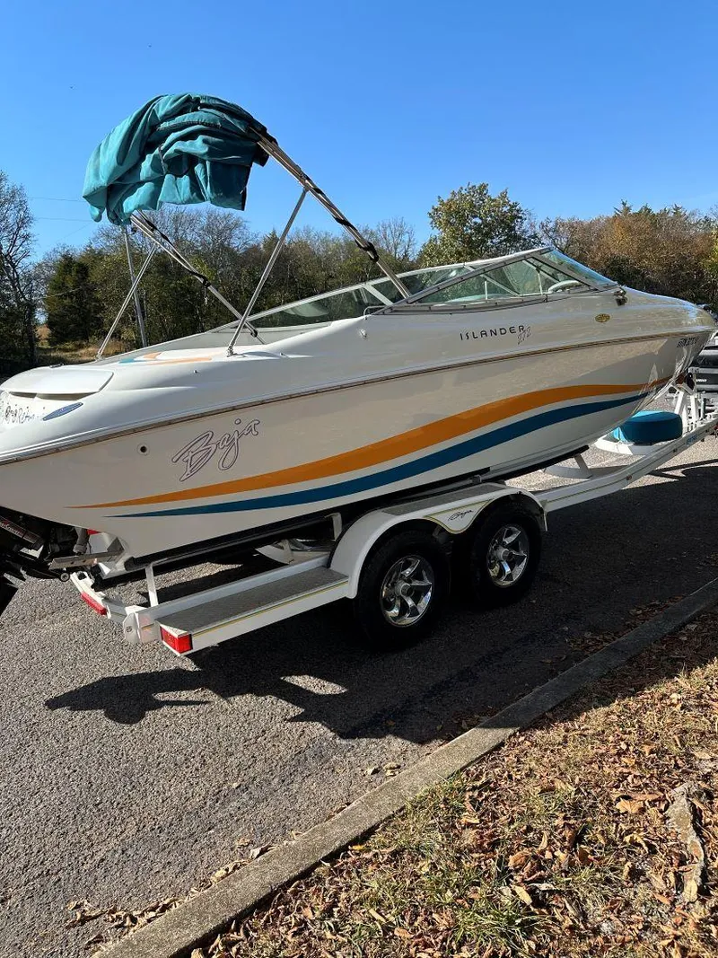 Slide: The Image of 1995 Baja 272 Islander boat on trailer, white with orange and blue stripes, parked outdoors. - 5