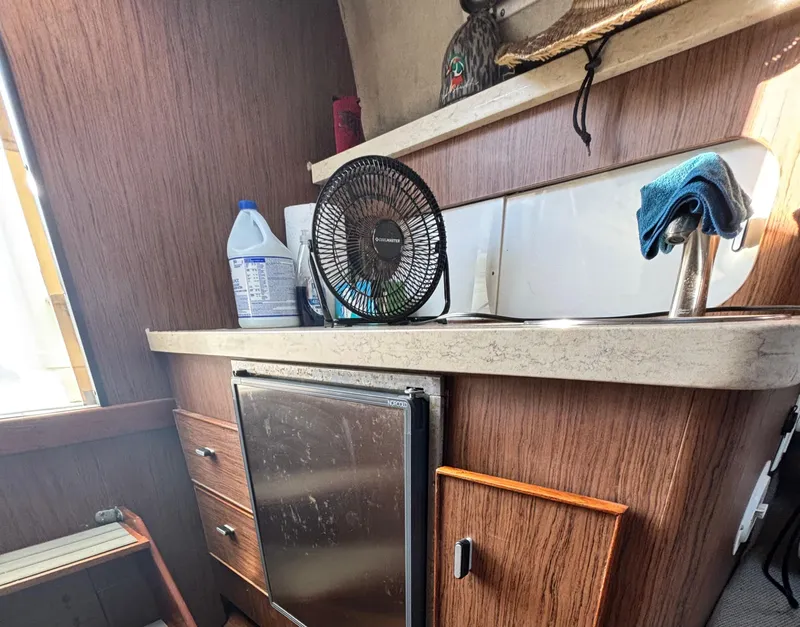 Slide: The Image of 1992 Pursuit 2800 Open boat interior with kitchenette, fan, and mini fridge. - 11