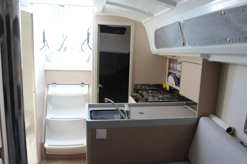 Slide: The Image of Interior of 2022 Beneteau Oceanis 30.1 yacht, featuring modern kitchen and compact design. - 17
