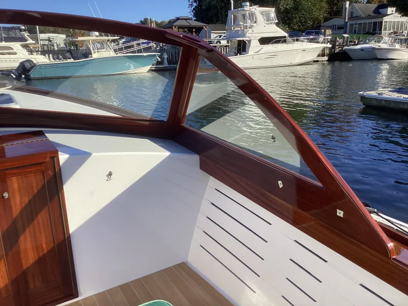 Slide: The Image of 2024 MacKenzie Cuttyhunk boat interior with wooden trim, docked at marina. - 10