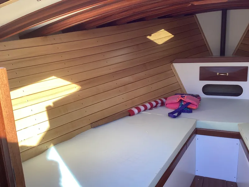 Slide: The Image of 2024 MacKenzie Cuttyhunk boat interior with wooden paneling and storage. - 13