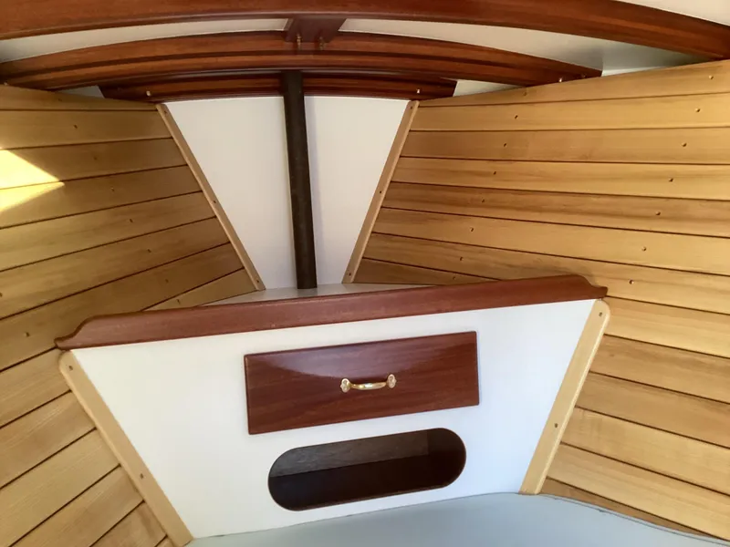 Slide: The Image of 2024 MacKenzie Cuttyhunk boat interior with wooden paneling and storage compartment. - 16