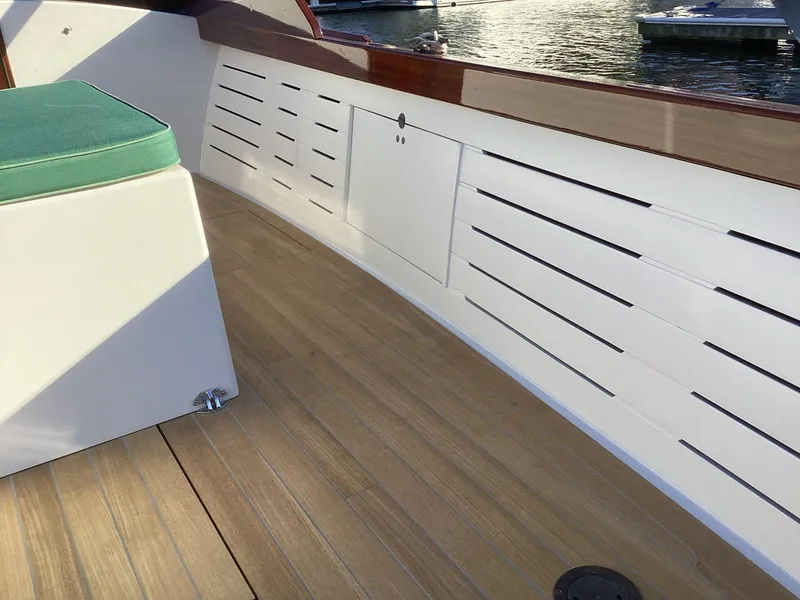 Slide: The Image of 2024 MacKenzie Cuttyhunk boat interior with wooden deck and green cushioned seating. - 20
