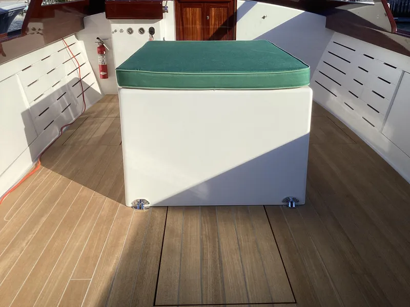 Slide: The Image of 2024 MacKenzie Cuttyhunk boat interior with green cushioned seat and wooden flooring. - 21