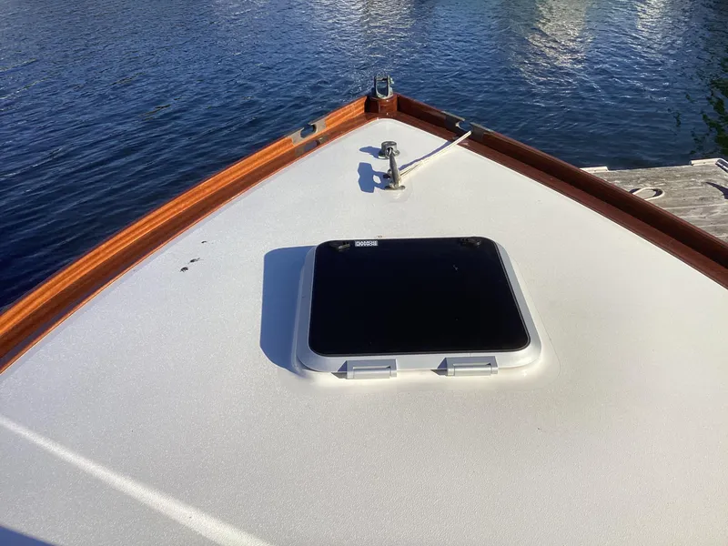 Slide: The Image of 2024 MacKenzie Cuttyhunk boat deck with hatch, docked on calm water. - 23