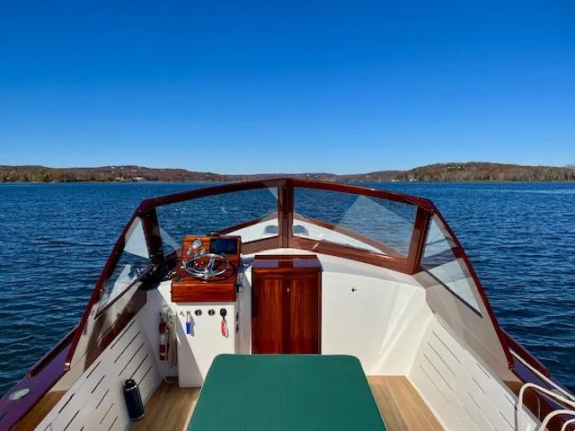 Slide: The Image of 2024 MacKenzie Cuttyhunk boat on a serene lake under clear blue skies. - 44