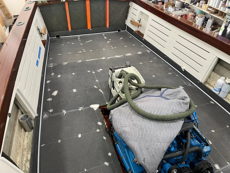 Slide: The Image of 2024 MacKenzie Cuttyhunk boat interior under construction with visible engine and tools. - 47