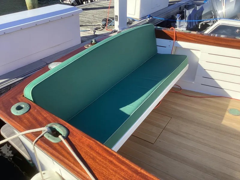 Slide: The Image of Green cushioned bench on 2024 MacKenzie Cuttyhunk boat with wooden deck. - 6