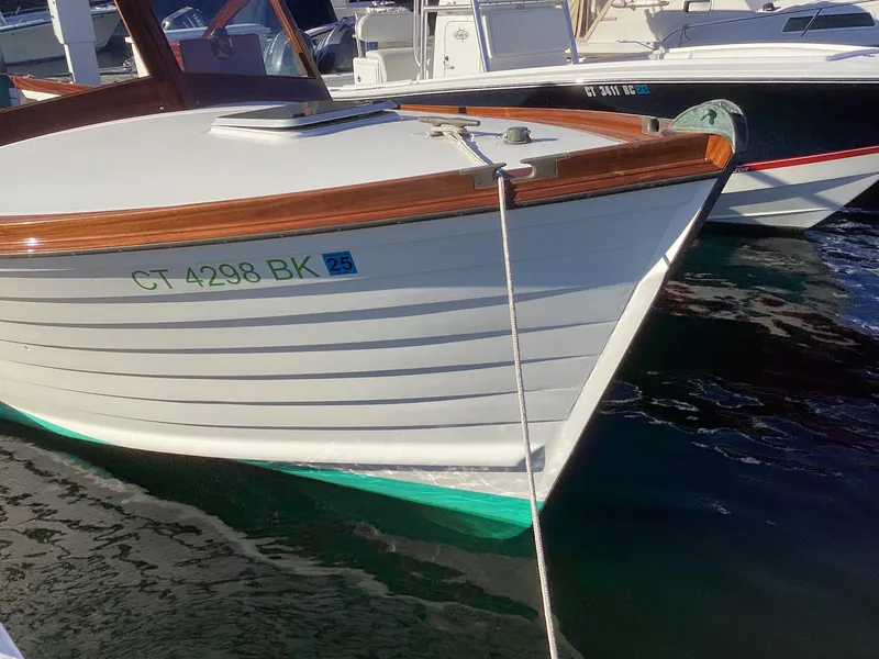 Slide: The Image of 2024 MacKenzie Cuttyhunk boat docked, featuring a sleek white hull and wooden trim. - 7