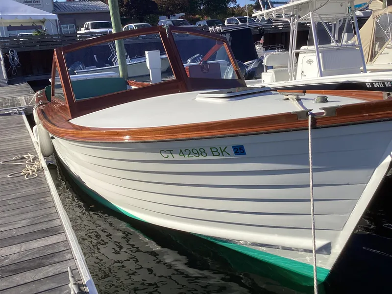 Slide: The Image of 2024 MacKenzie Cuttyhunk boat docked at marina, featuring wooden trim and sleek design. - 8