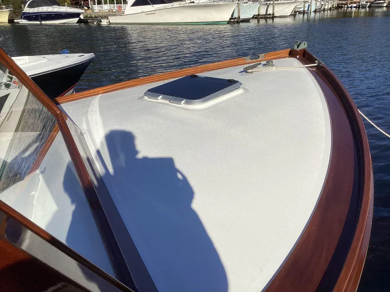 Slide: The Image of 2024 MacKenzie Cuttyhunk boat deck with wooden trim, docked in a marina. - 9